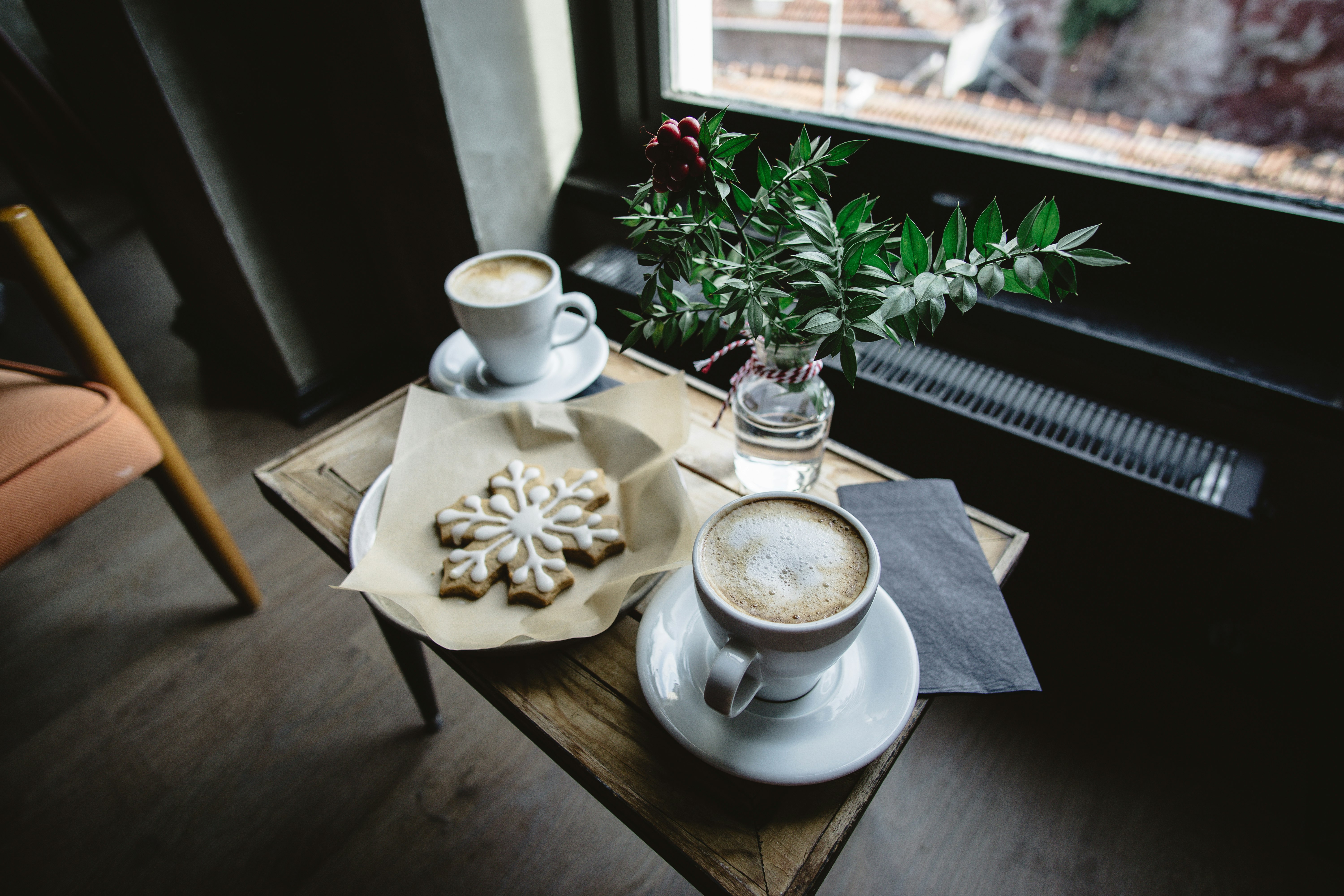 two cups of coffees on brown wooden coffee table besie glass window